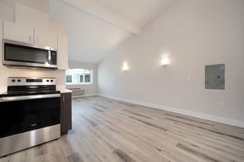 An empty kitchen and living room with white walls and wood flooring